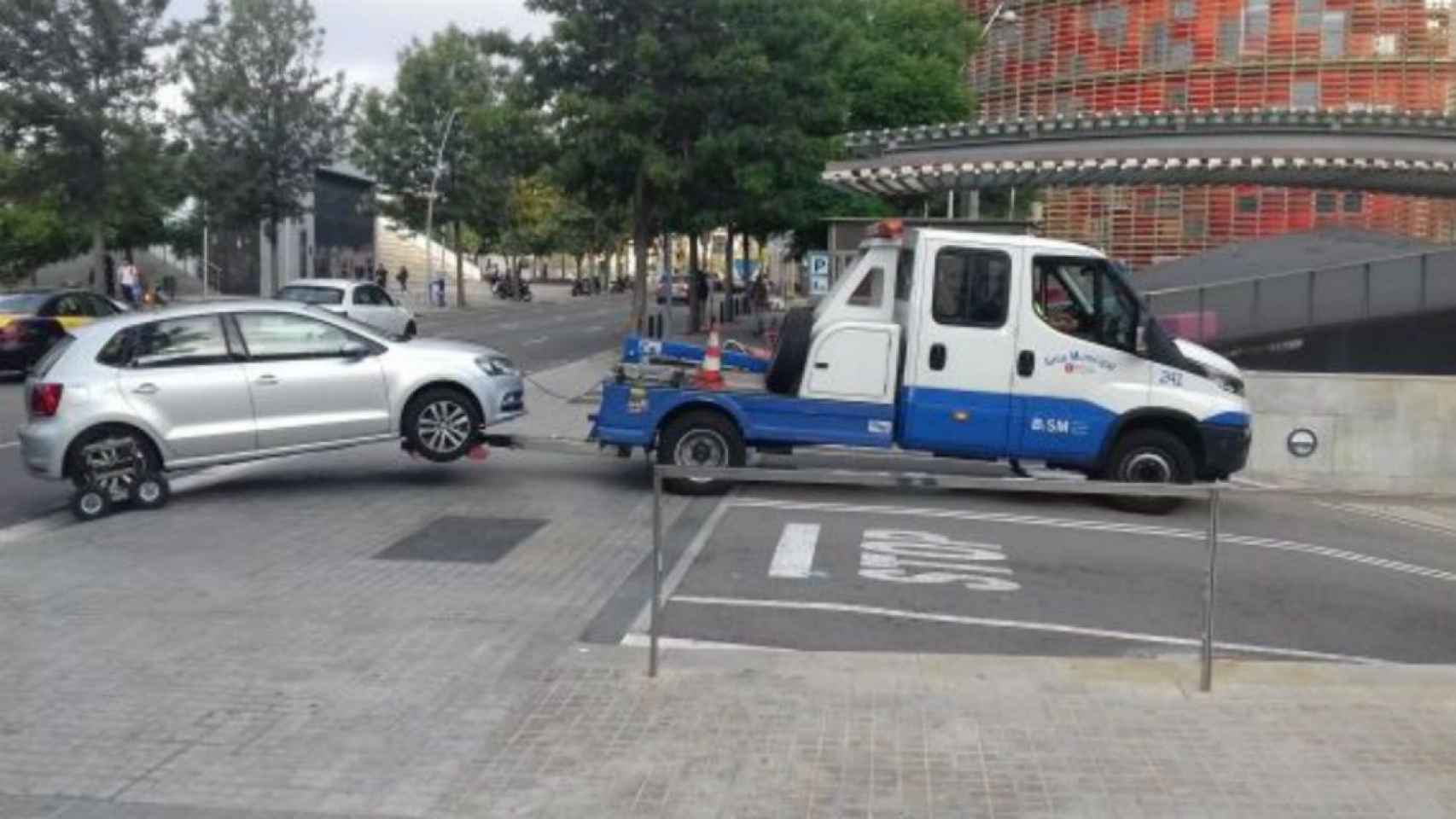 Una grúa municipal entra con un coche enganchado en el depósito de Glòries / JORDI SUBIRANA