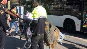 Un guardia urbano para a un chatarrero vestido con una vieja chaqueta de la policía local barcelonesa.