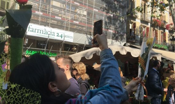 Una joven fotografiando una rosa amarilla en Sant Jordi / P. B.