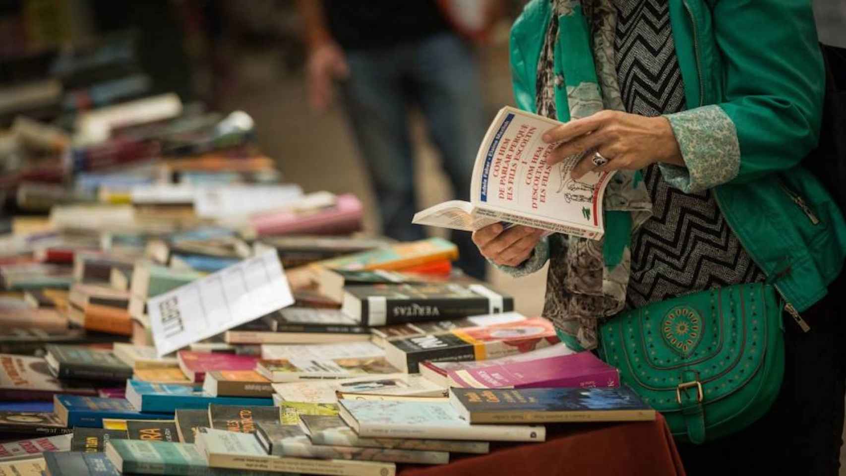 Una lectora ojeando libros en una parada durante la diada de Sant Jordi / EFE