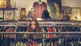Chica buscando ropa en una tienda de moda vintage