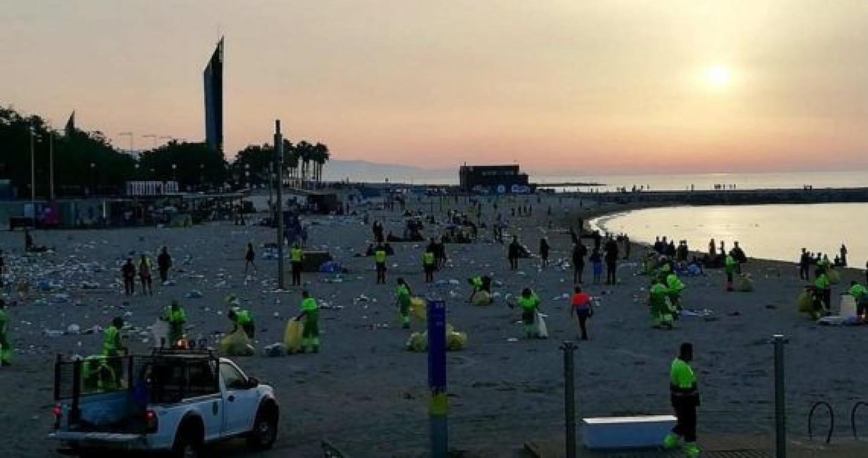 Agentes limpiando una playa de Barcelona tras la verbena de Sant Joan