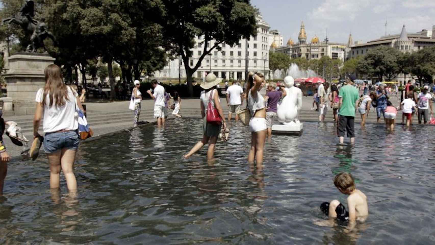 Turistas se bañan en las fuentes de plaça Catalunya durante una ola de calor en Barcelona
