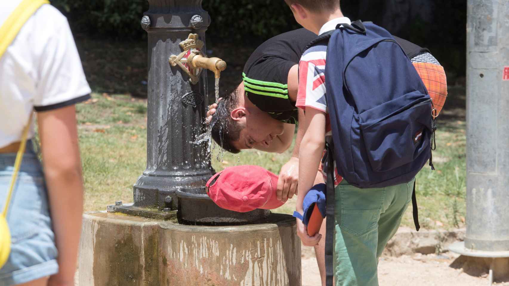 Un hombre mojándose la cabeza con agua en Barcelona durante la ola de calor