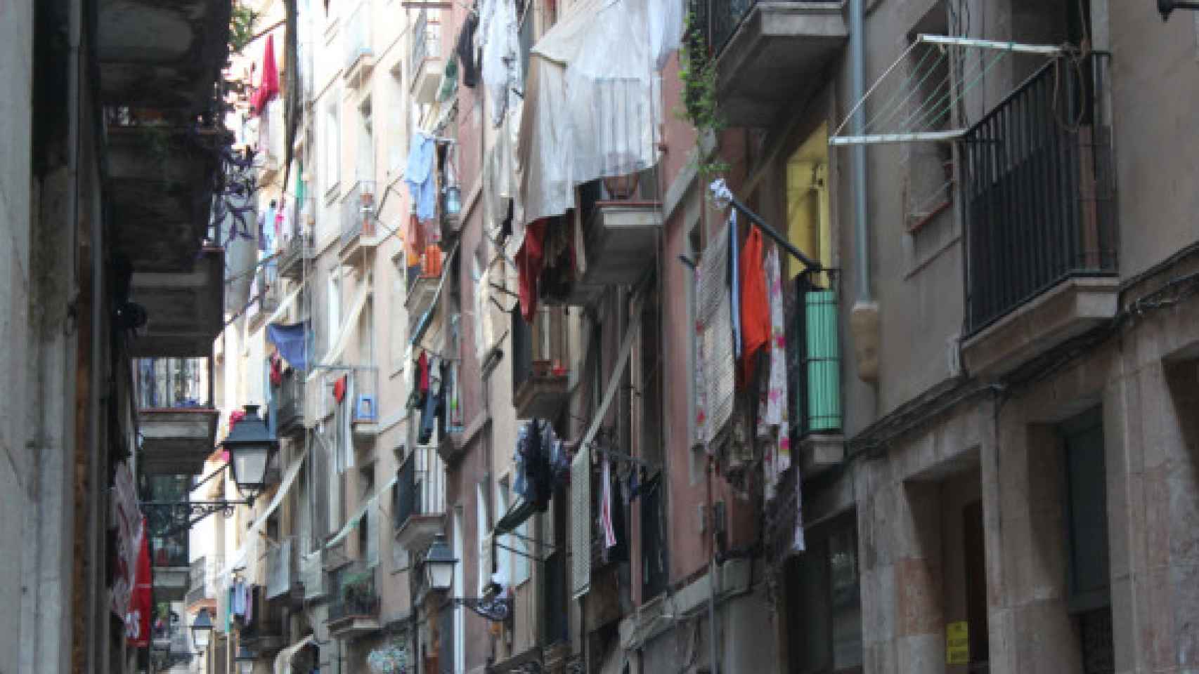 Calle estrecha llena de ropa colgada de los balcones en el barrio del Raval de Barcelona