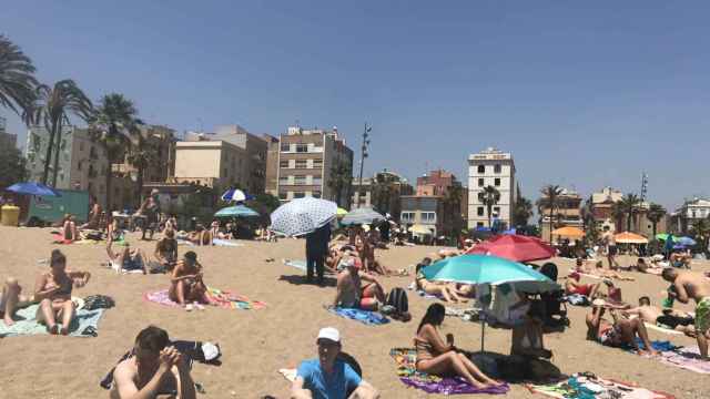 Un vendedor ambulante alquilando sombrillas en la playa de la Barceloneta / MA