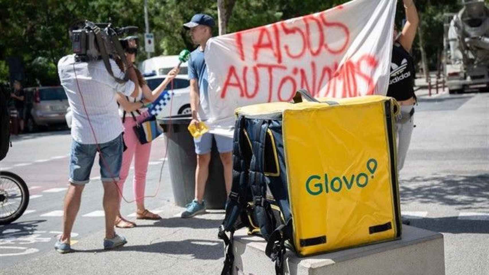 Un trabajador de Glovo manifestándose con un cartel de falsos autónomos / EP