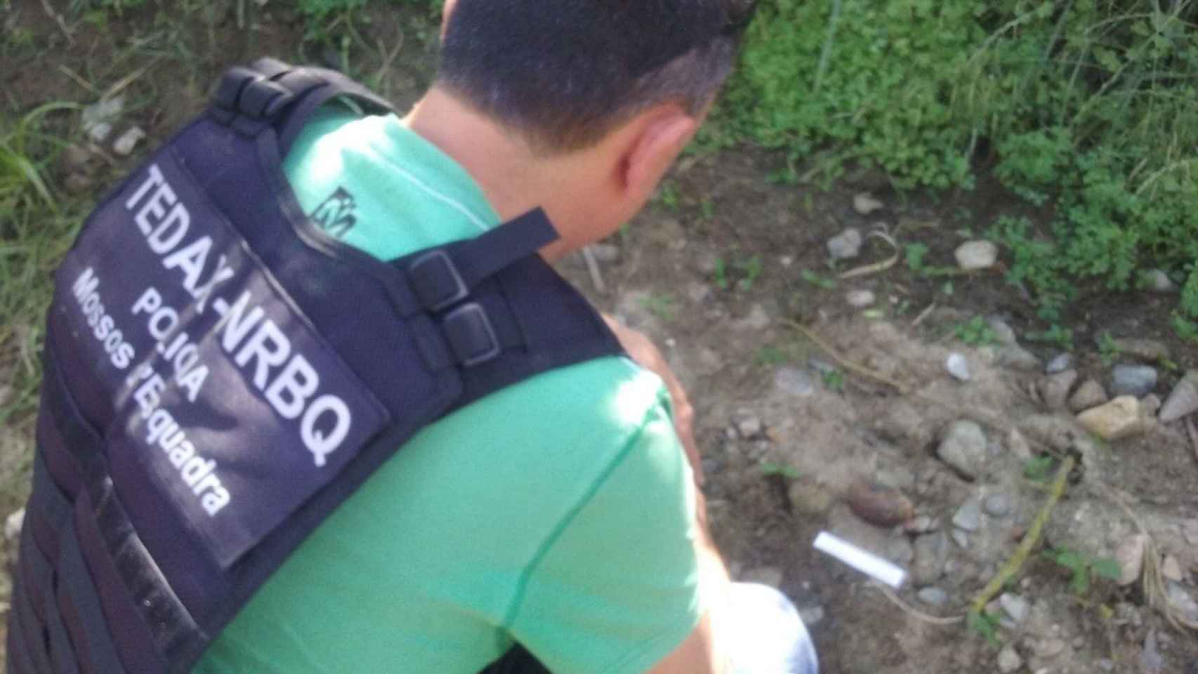 Un mosso d'esquadra junto a una granada hallada en unos terrenos / MOSSOS D'ESQUADRA