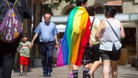 Una pareja camina por la calle con la bandera arcoiris, emblema del colectivo LGTBI / EFE