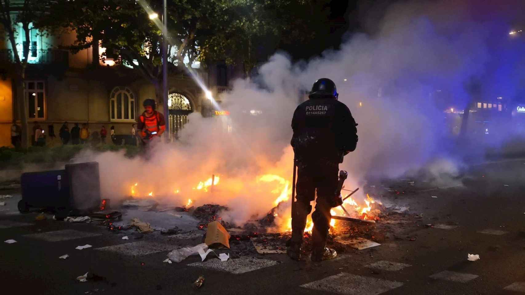 Un policía y un bombero al lado de un incendio generado durante la manifestación / EP