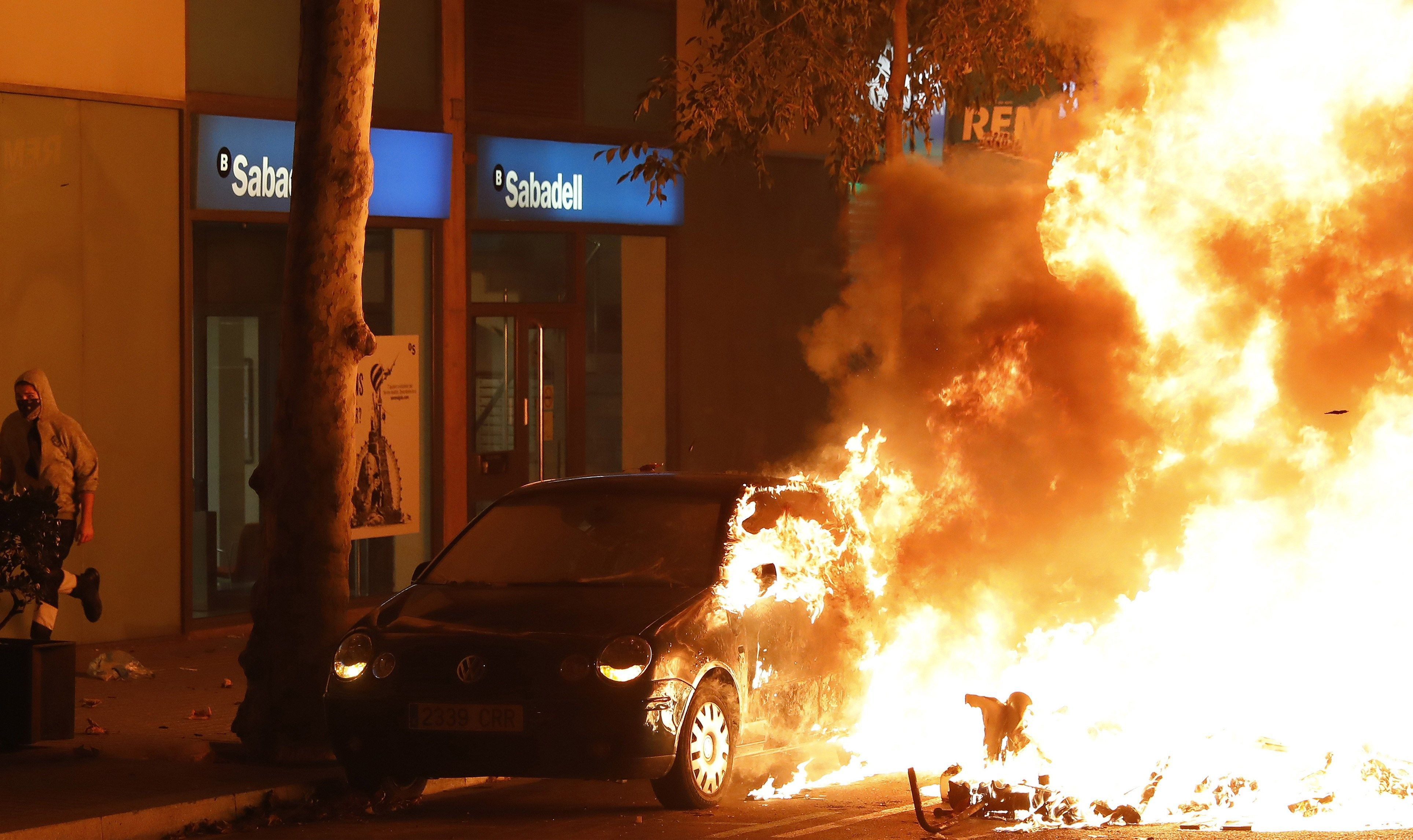 Un coche arde durante los disturbios que se están produciendo tras la concentración este miércoles de miles de personas ante la conselleria de Interior en Barcelona / EFE - Andreu Dalmau