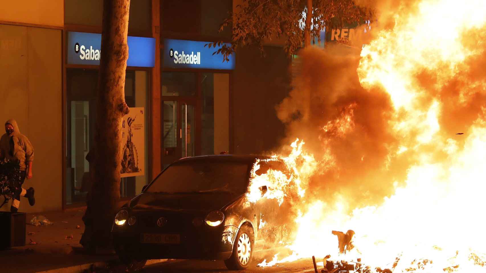 Un coche arde durante los disturbios que se están produciendo tras la concentración este miércoles de miles de personas ante la conselleria de Interior en Barcelona / EFE - Andreu