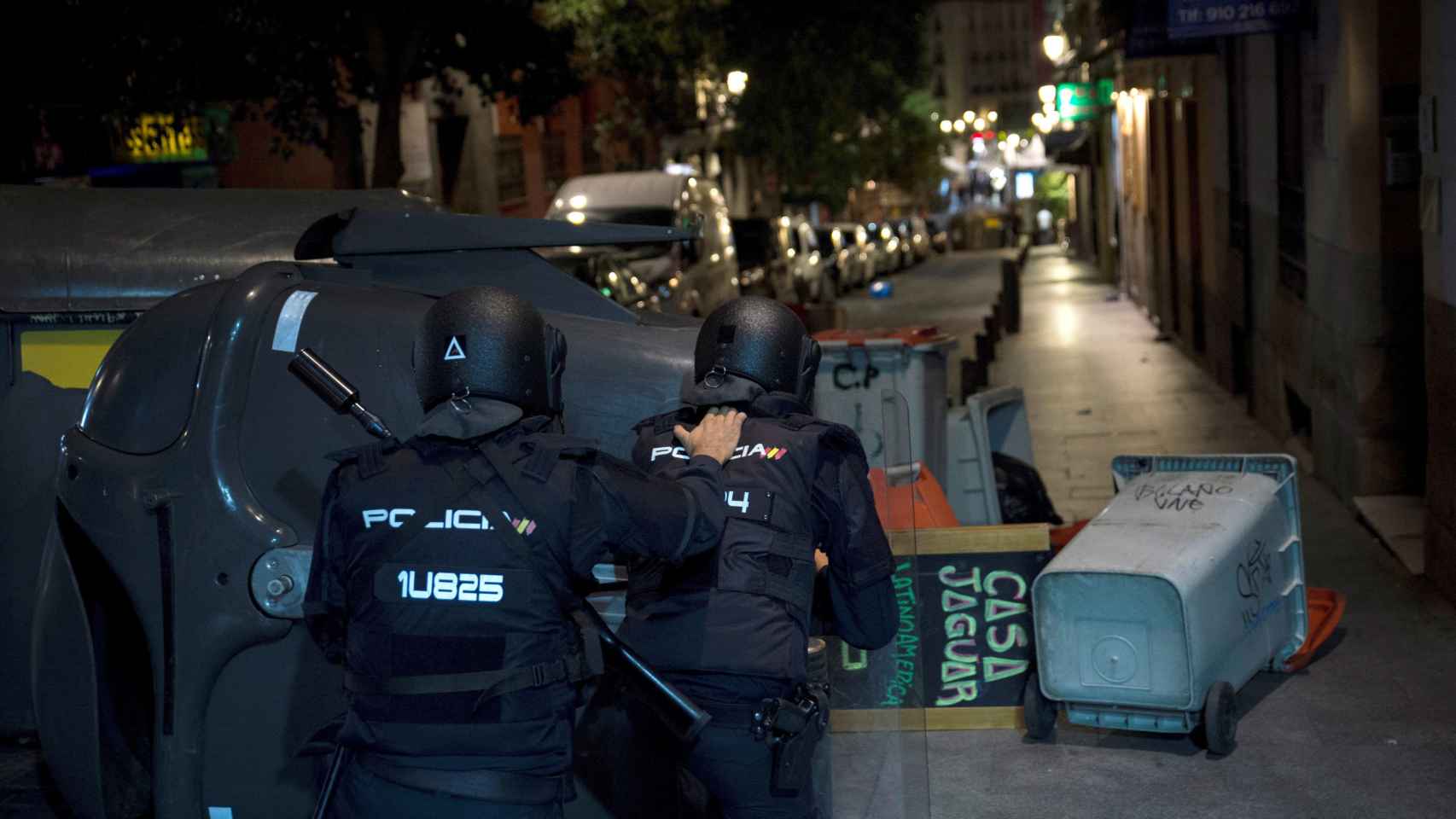 Dos policías junto a varios contenedores tumbados en la vía / EFE