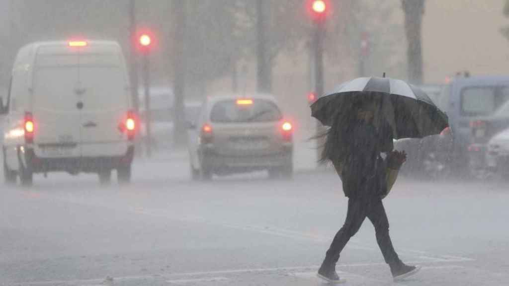 Una persona cruza una calle durante un día de lluvia