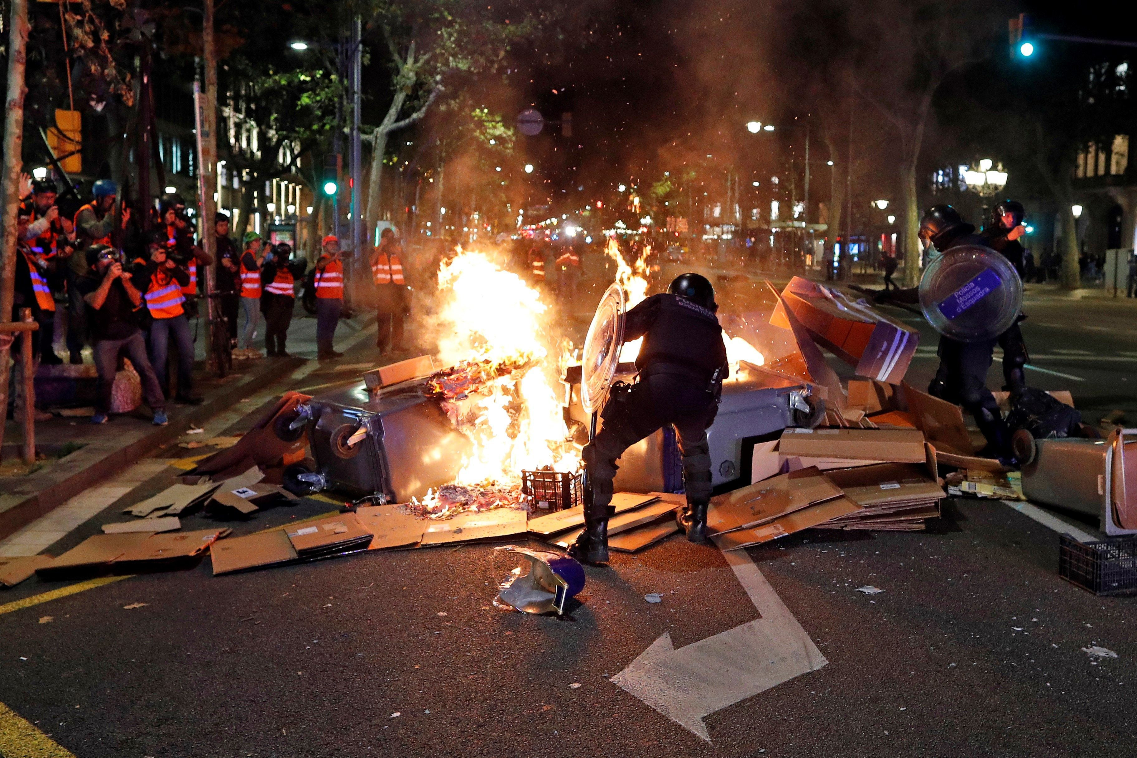 Los Mossos apartan objetos para evitar que se propague el fuego de una barricada / EFE