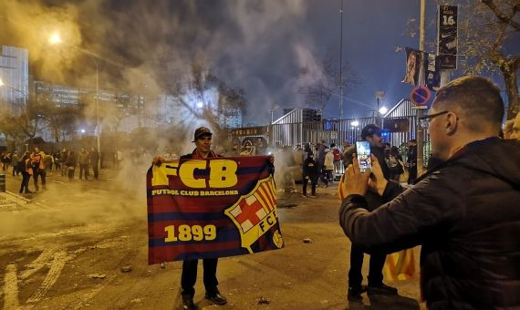 Un turista se hace una foto con los restos humeantos de una barricada de fondo