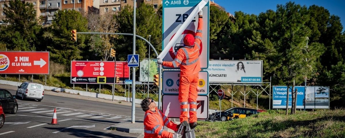 Unos operarios instalan unas señales de la ZBE / AMB