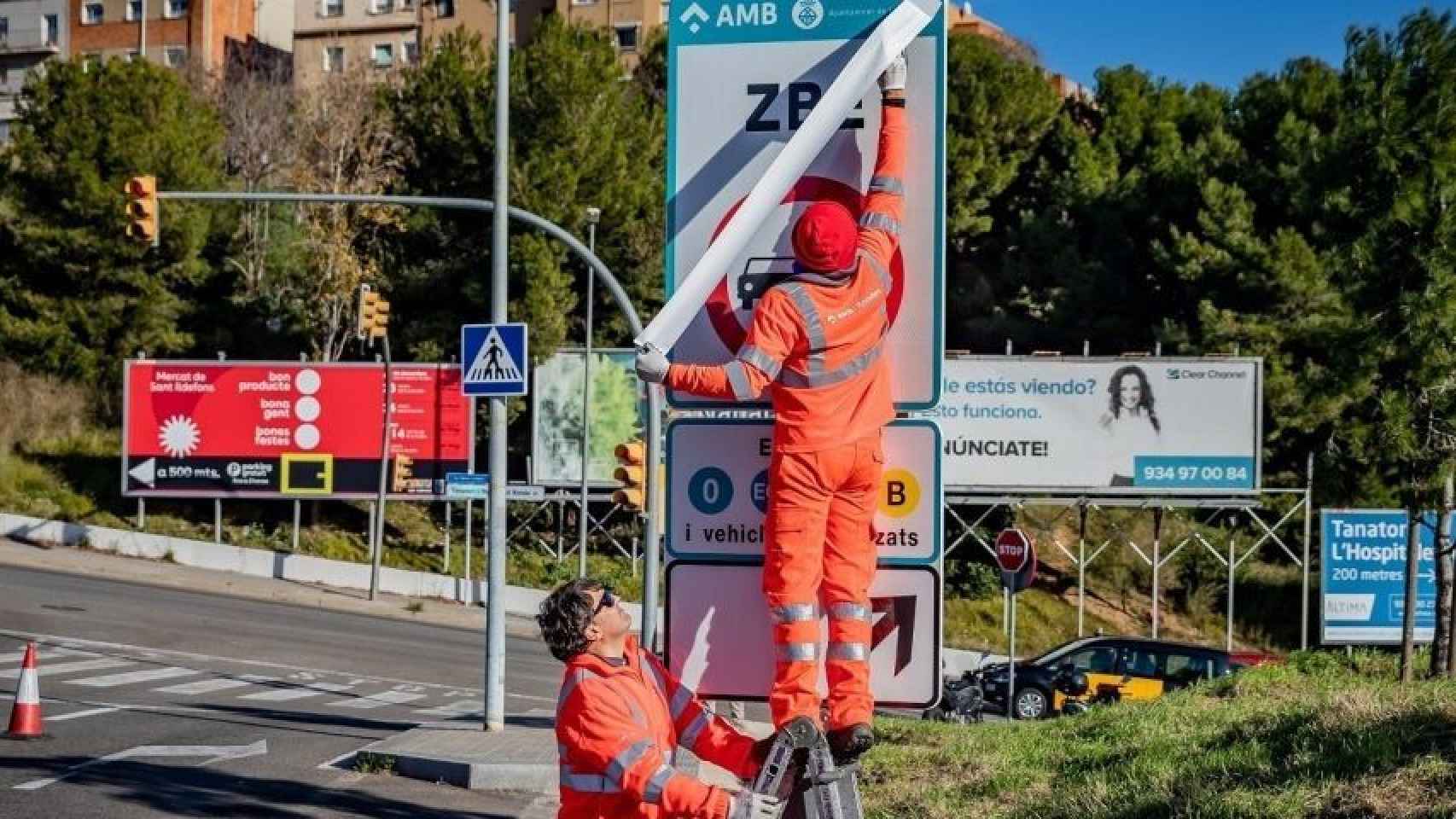 Unos operarios instalan unas señales de la ZBE / AMB