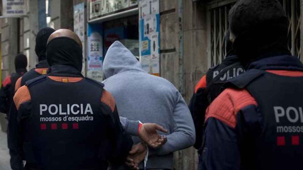 Unos mossos se llevan a un detenido en una operación policial / EFE