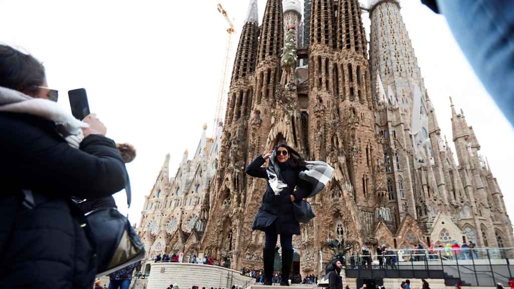 Turistas se fotografían ante la Sagrada Familia en un día de fuerte viento