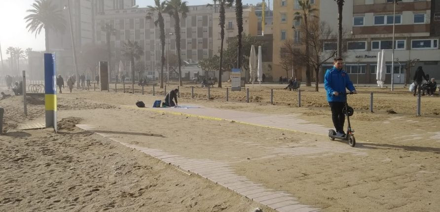 Un mantero, en el paseo Marítim de la Barceloneta lleno de arena / JORDI SUBIRANA