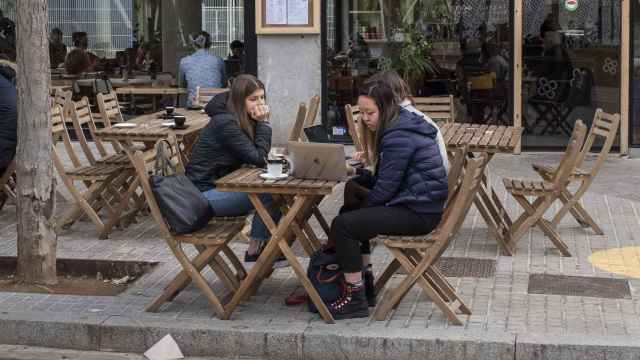 Tres chicas consultan un ordenador portátil mientras se toman un café en un restaurante vegano / Lena Prieto