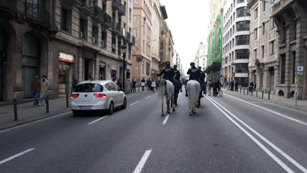 Agentes de la Guardia Urbana a caballo junto a un coche en Via Laietana / M A