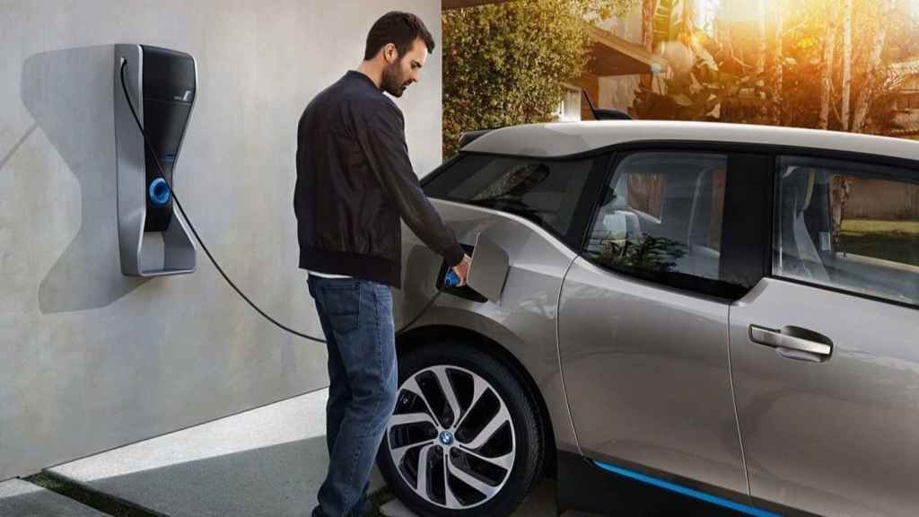 Un hombre carga su vehículo eléctrico