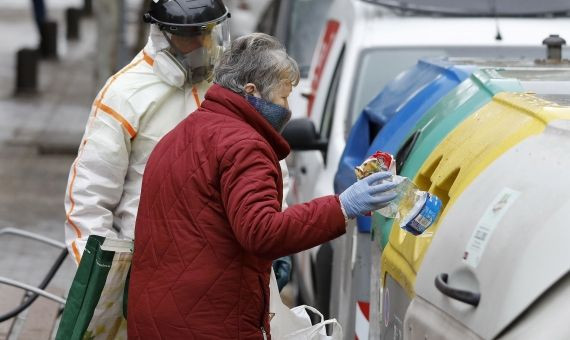 Una mujer tira la basura bajo la atenta mirada de un operario