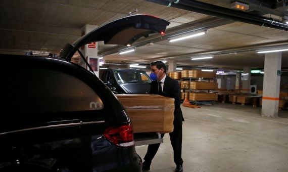 Un trabajador del tanatorio de Collserola introduce el féretro en el coche fúnebre / EFE - QUIQUE GARCÍA 