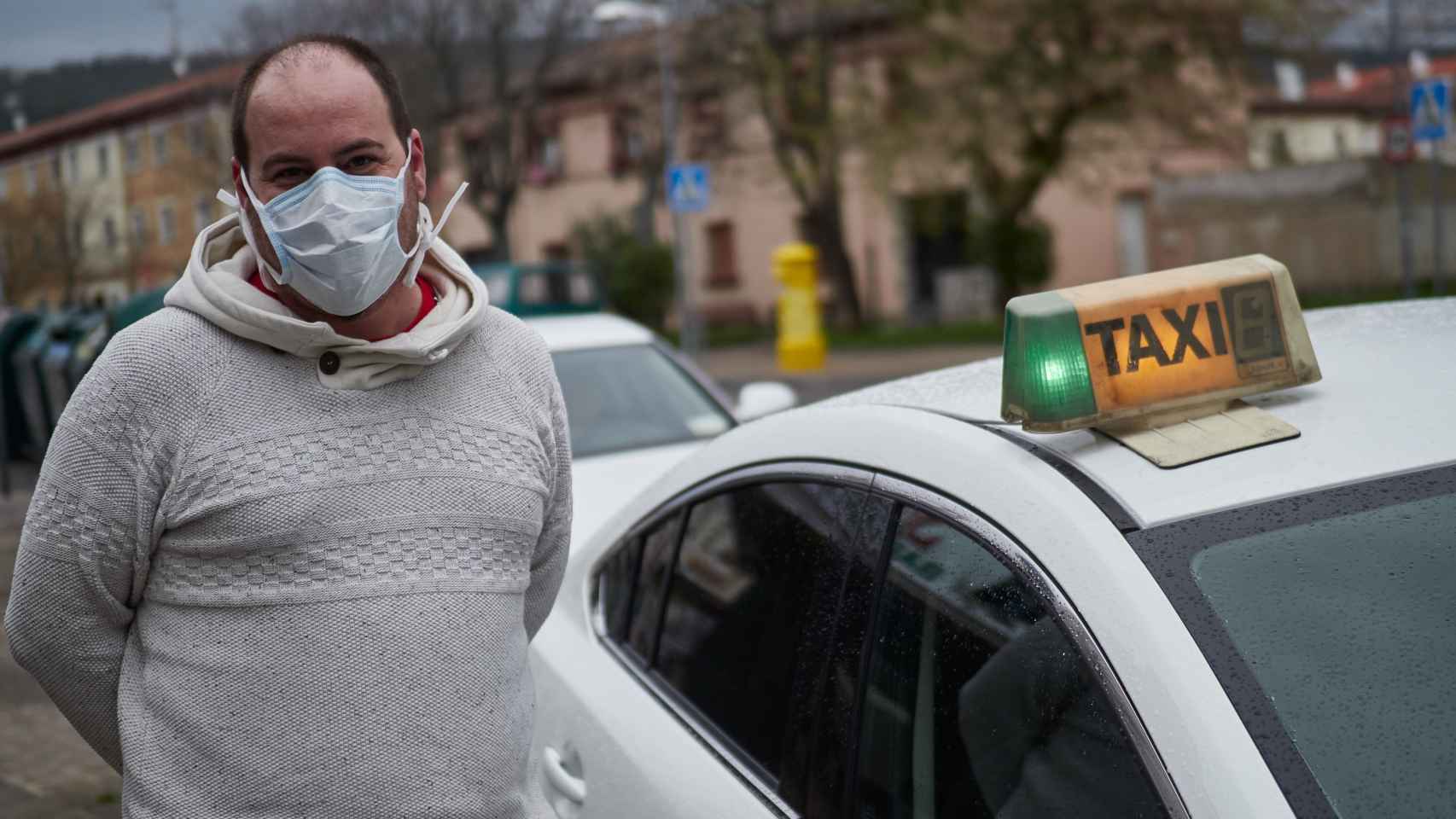 El conductor de un taxi con una mascarilla puesta para cubrirse la nariz y la boca