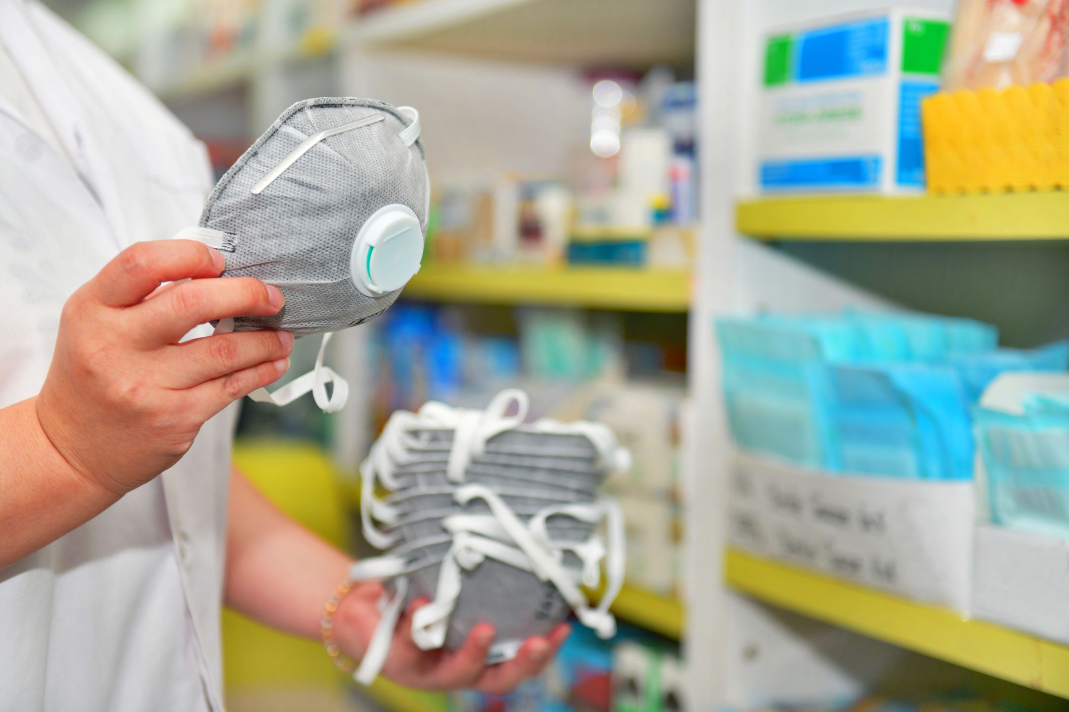 Una persona en una farmacia con varias mascarillas en la mano