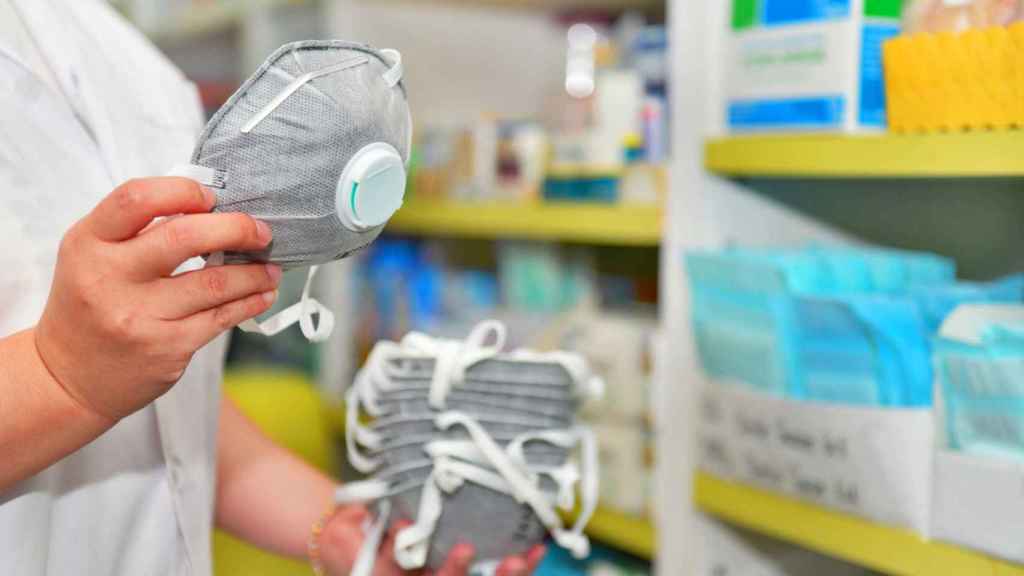 Una persona en una farmacia con varias mascarillas en la mano