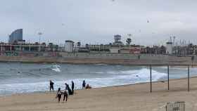 Surfistas y bañistas desafían al oleaje en la playa de Bogatell / V.M.