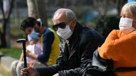 Gente mayor sentada en un banco con mascarilla / REUTERS