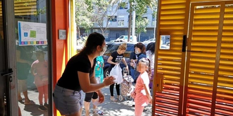 Una educadora habla con una niña en la puerta de la escuela de La Mina / G.A