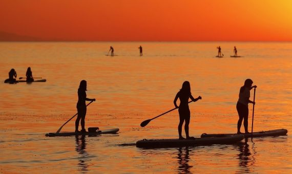 Gente pracitcando paddle surf en la playa de la Barceloneta a primera hora este jueves / EFE - ANDREU DALMAU