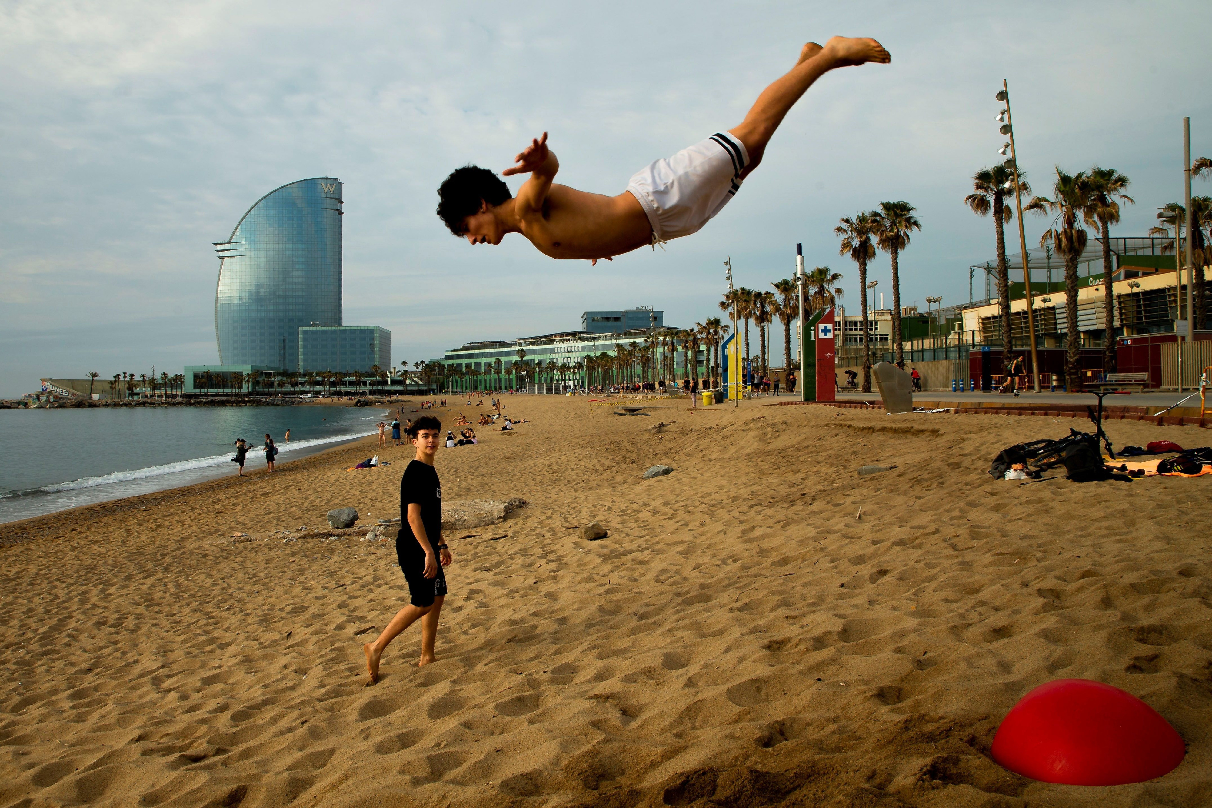 Un saltimbanqui practicando una acrobacia en una playa de la Barceloneta / EFE - Enric Fontcuberta