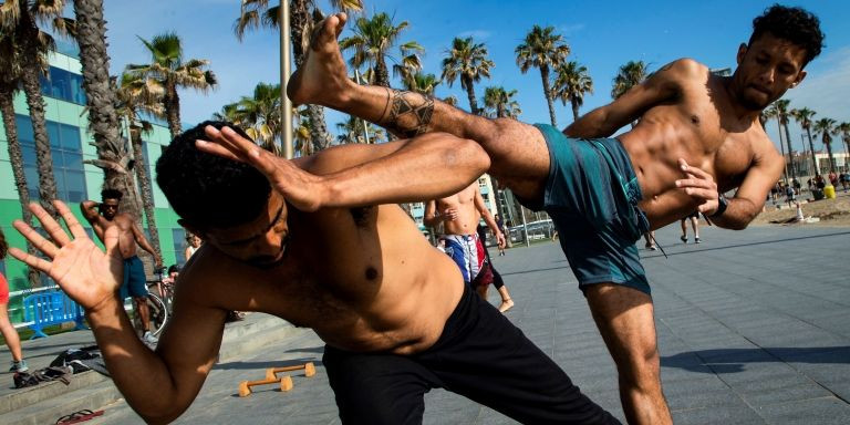 Dos jóvenes practican capoeira en la playa de Sant Sebastià de la Barceloneta / EFE - Enric Fontcuberta