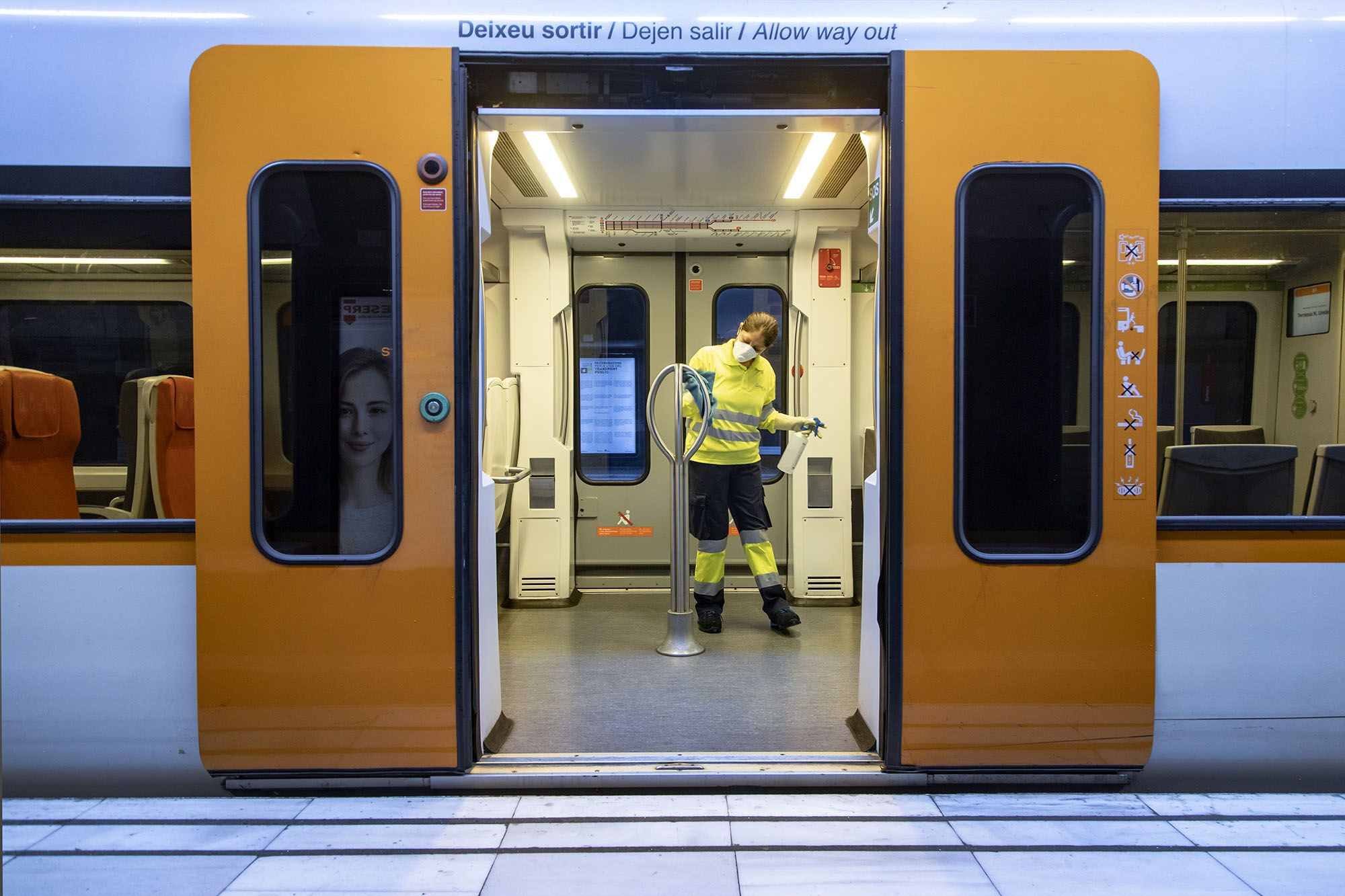 Interior de un tren con un operario desinfectando la zona