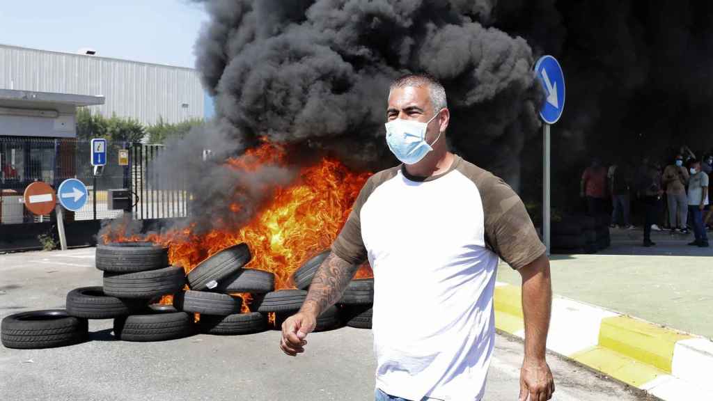 Un trabajador delante de la hoguera realizada con neumáticos