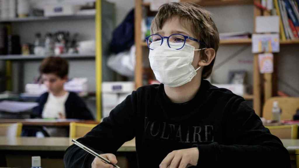 Un niño cubierto con una mascarilla dentro de una clase