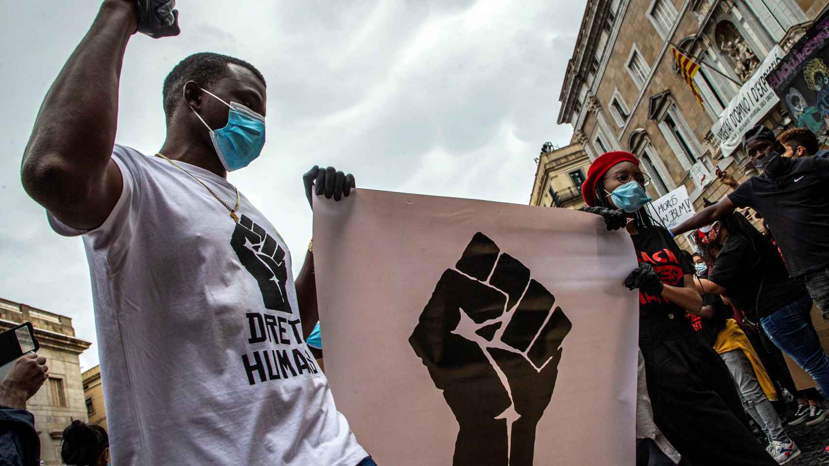 Un hombre protesta contra el racismo con una pancarta, ataviado con su mascarilla / EFE - Enric Fontcuberta