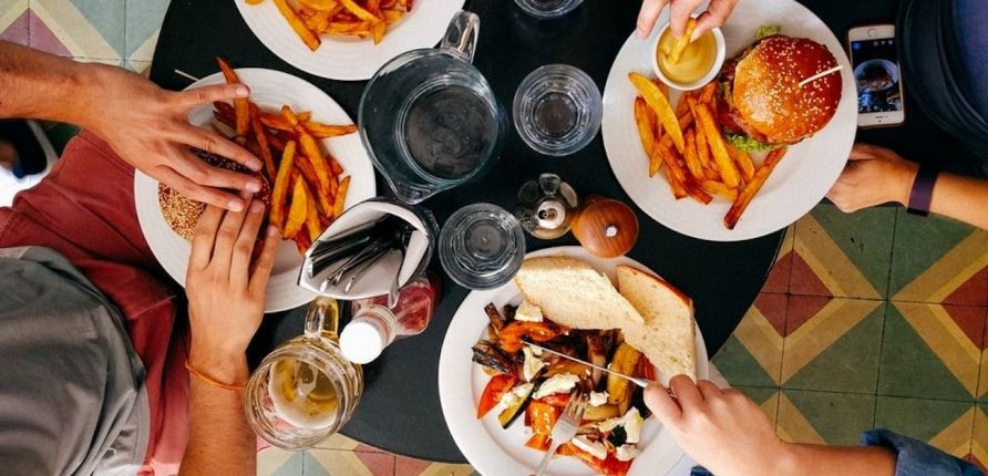 Cuatro comensales en un restaurante compartiendo una comida