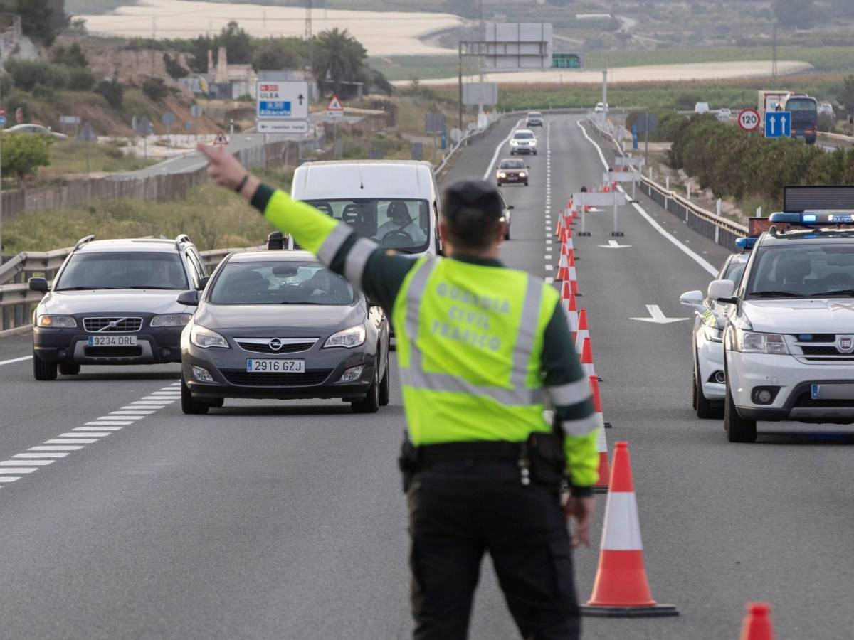 Un policía dirigiendo una decena de coches durante la pandemia / EFE