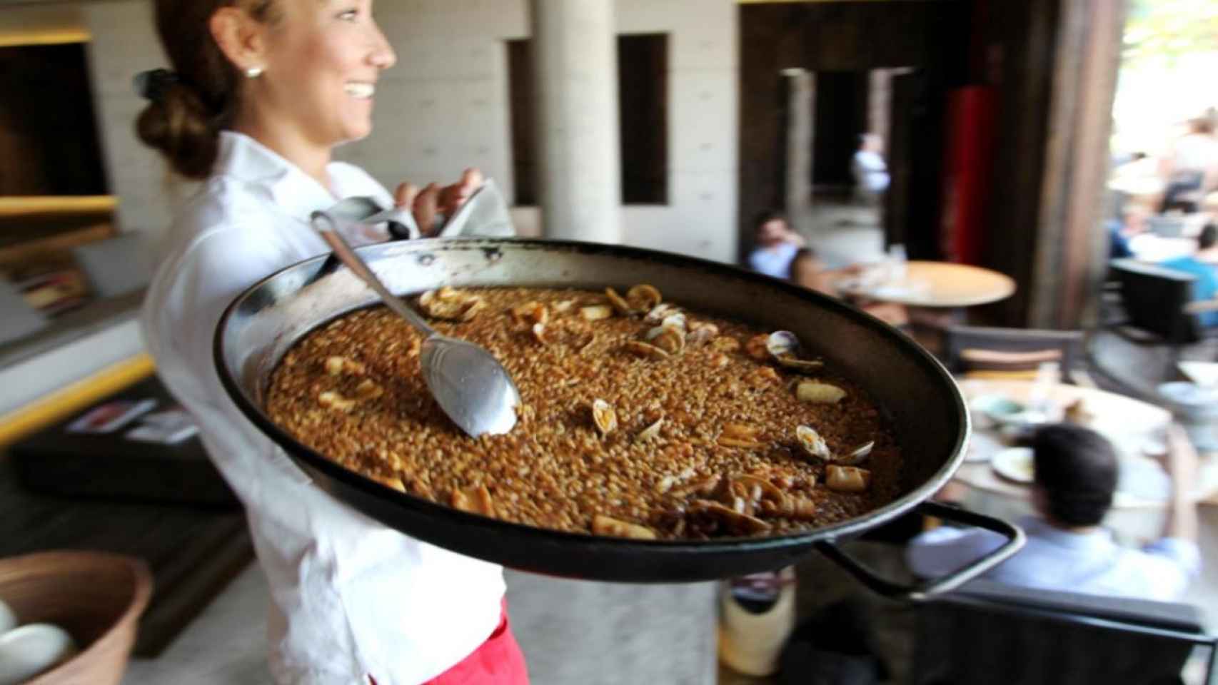 Una camarera del Pez Vela de Barcelona llevando una paella a una mesa / GRUPO TRAGALUZ