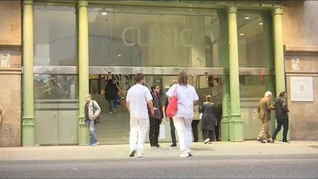 Exterior del Hospital Clínic de Barcelona con dos profesionales de la salud entrando por la puerta principal