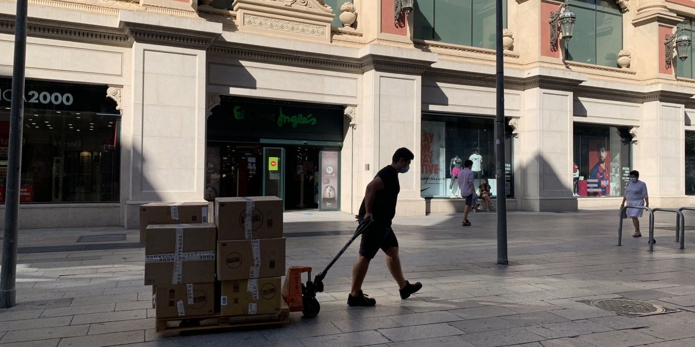 Un repartidor con cajas llenas de artículos desinfectados para las rebajas en Barcelona / V.M.