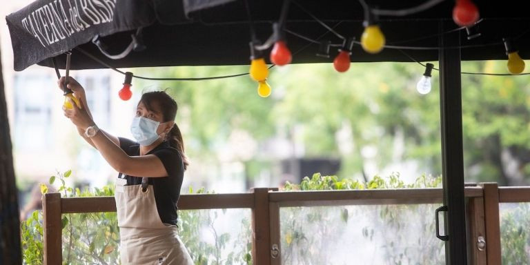 Una mujer con mascarilla abre una terraza en Ciutat Vella / EFE - MARTA PÉREZ