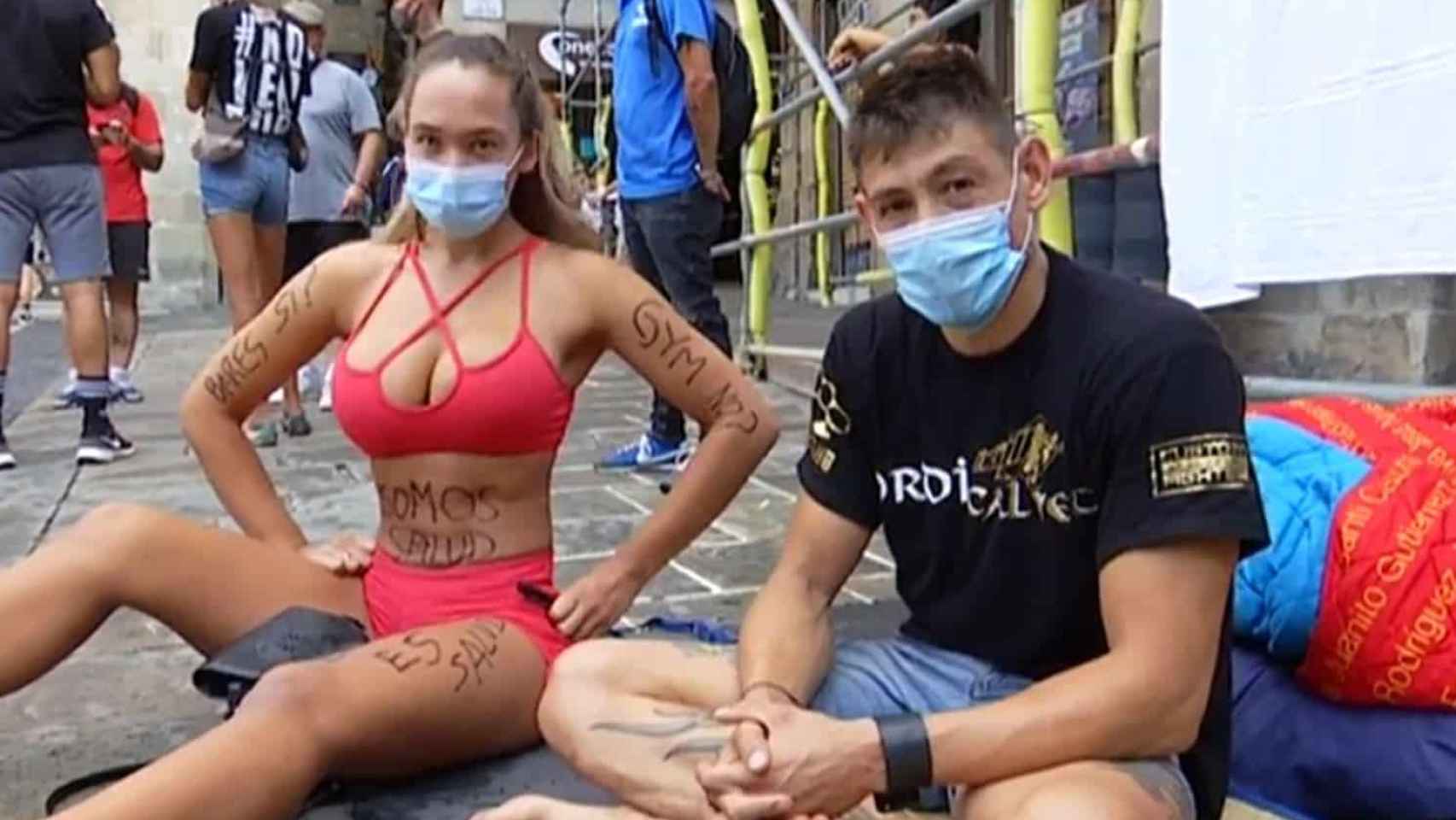 Dos personas sentadas en Plaza Sant Jaume reivindicando la reapertura de los gimnasios